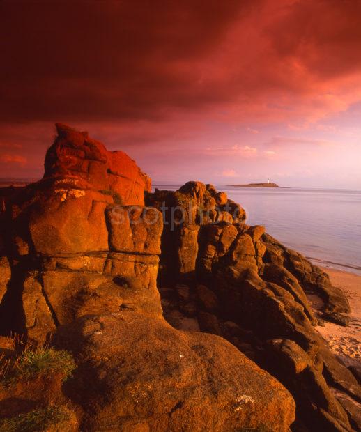 Dramatic Evening Sunlight Strikes The Sandstone Rocks Near Kildonan With Pladda Isle And Lighthouse In View Island Of Arran