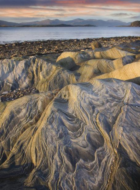 Folded Rocks On Island Of Eriska With The Morvern Hills Beyond