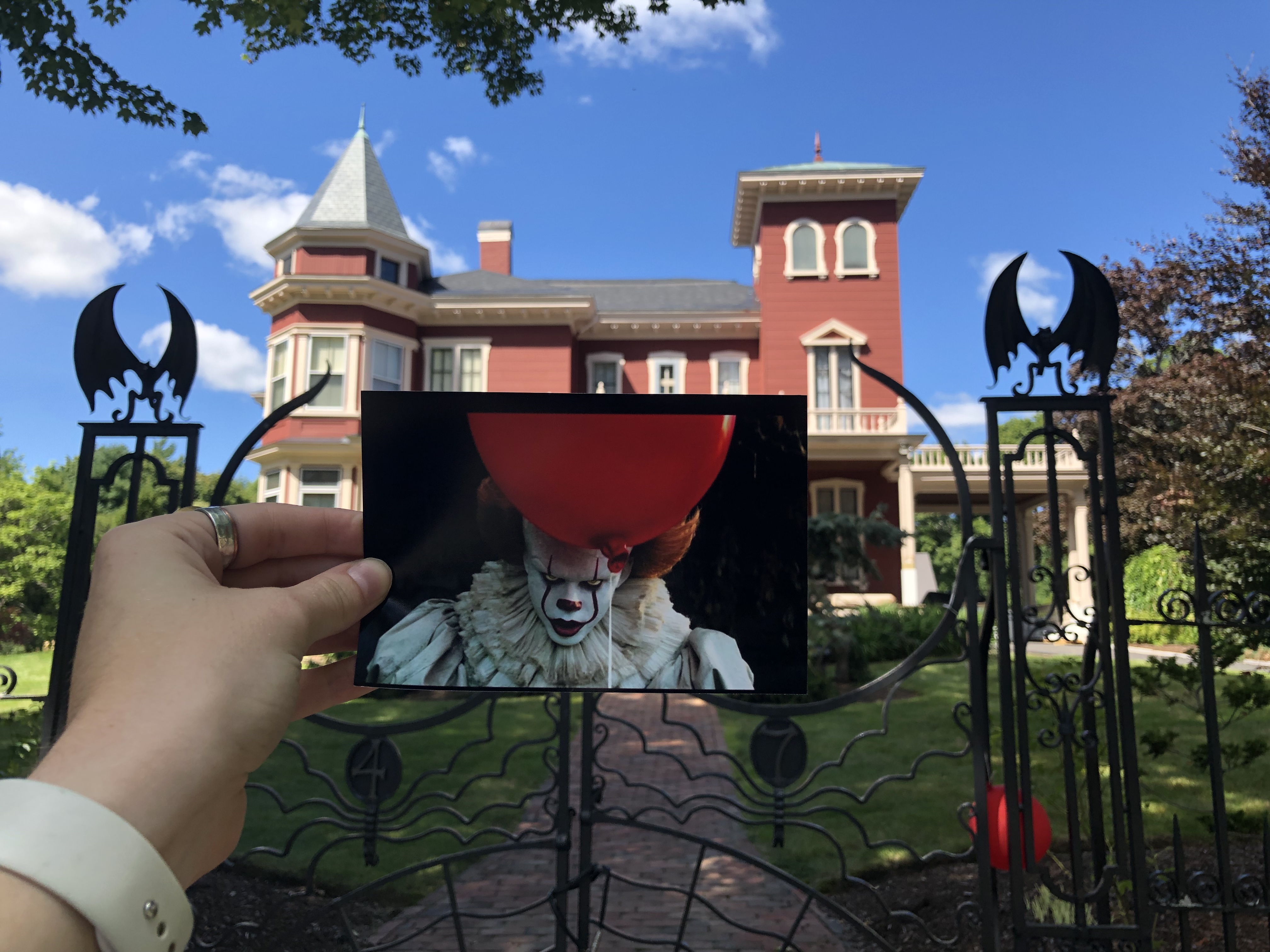 A photo taken from IT Chapter 1 of Pennywise holding a ballon placed outside Stephan Kings house.