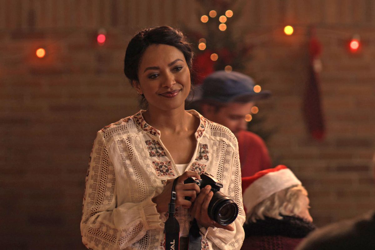 Abby is holding a camera and smiling at the people in front of her.