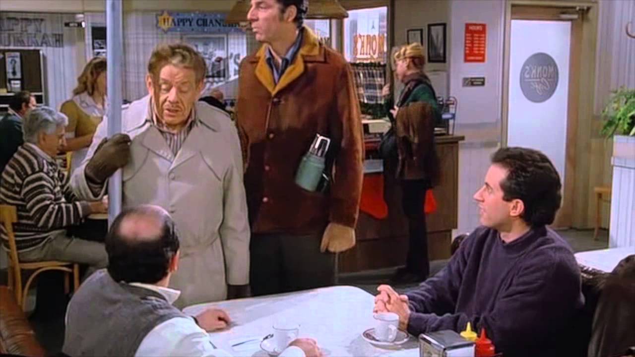 Jerry and George sit at a table and Frank and Kramer talk to them.