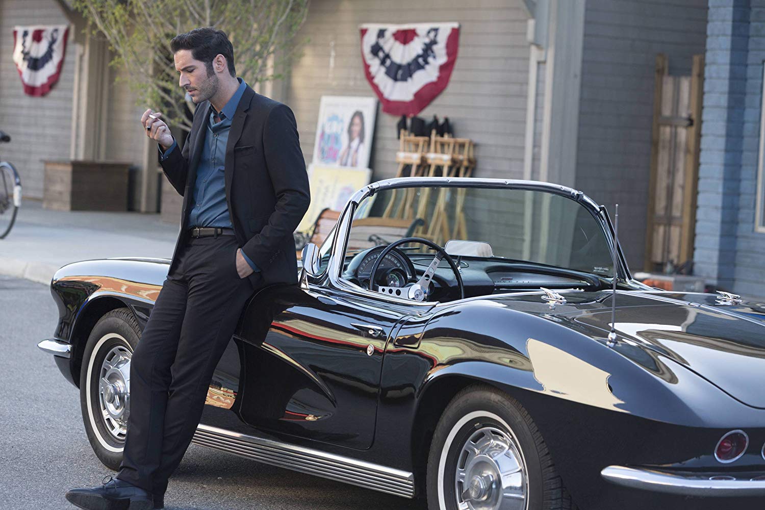 Lucifer Morningstar leans on a Corvette convertible.
