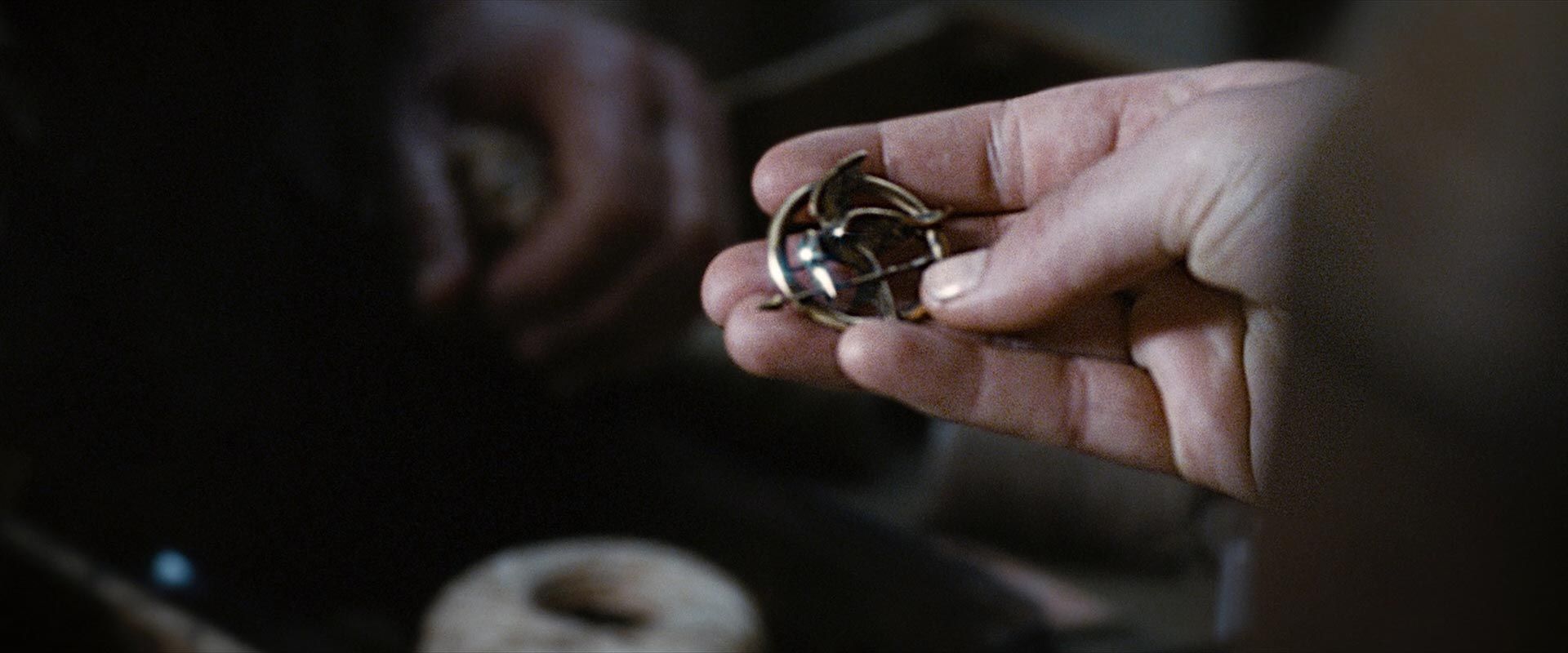 Katniss holds the Mockingjay pin at the Hob.