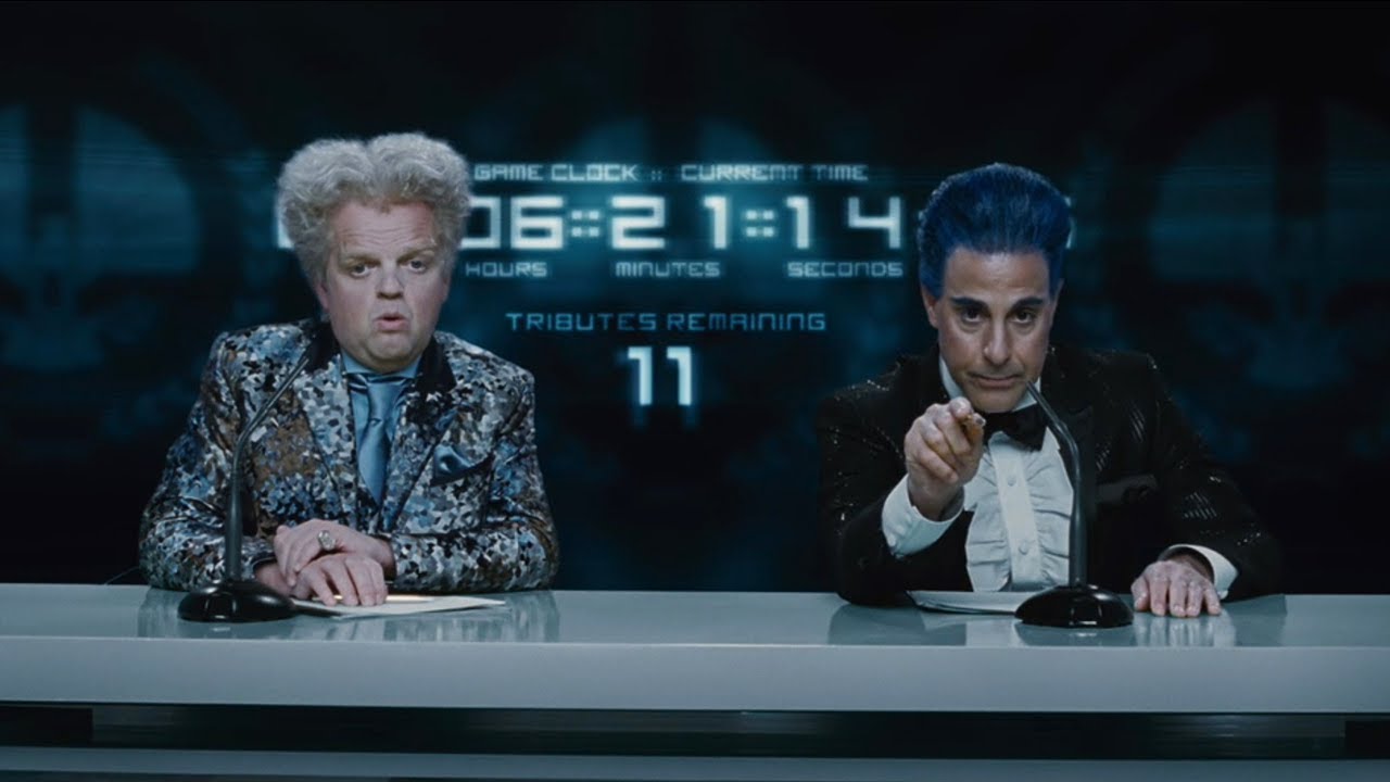 Claudius and Caesar sit in front of a countdown clock as commentators during the Games.