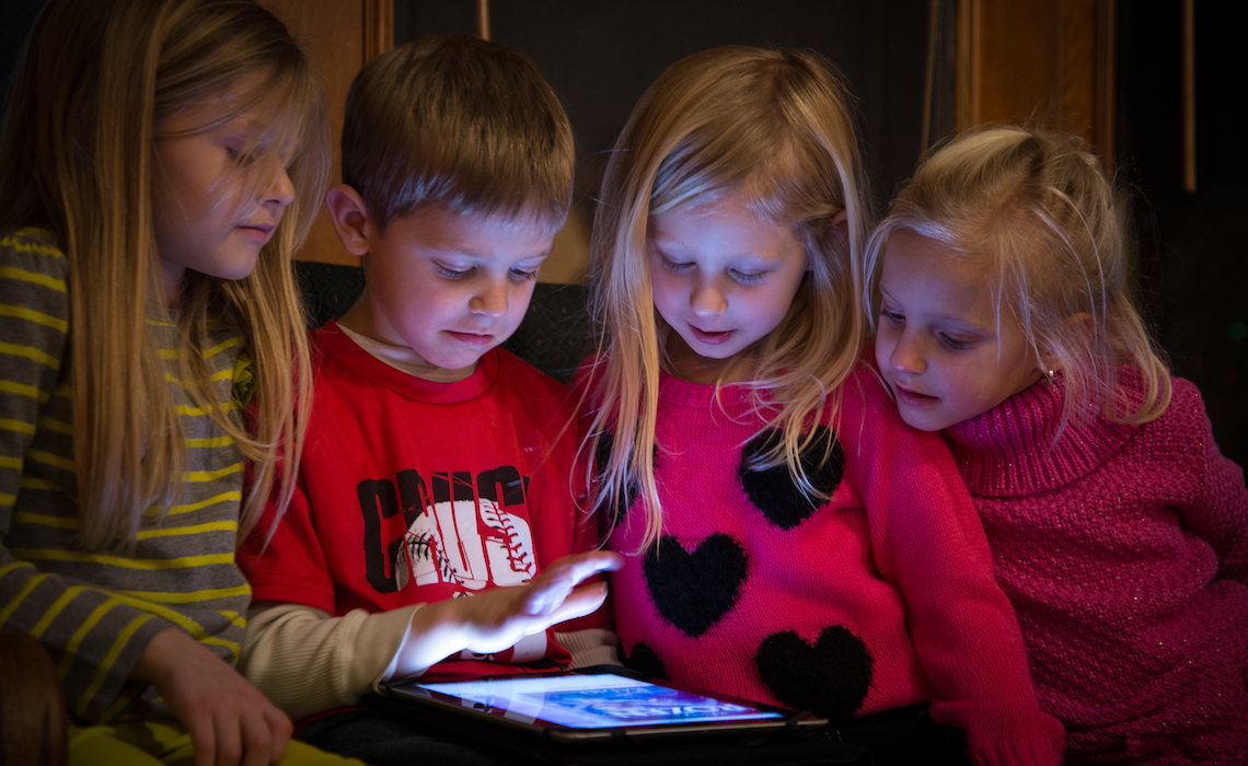 Children crowded around an iPad watching Youtube.