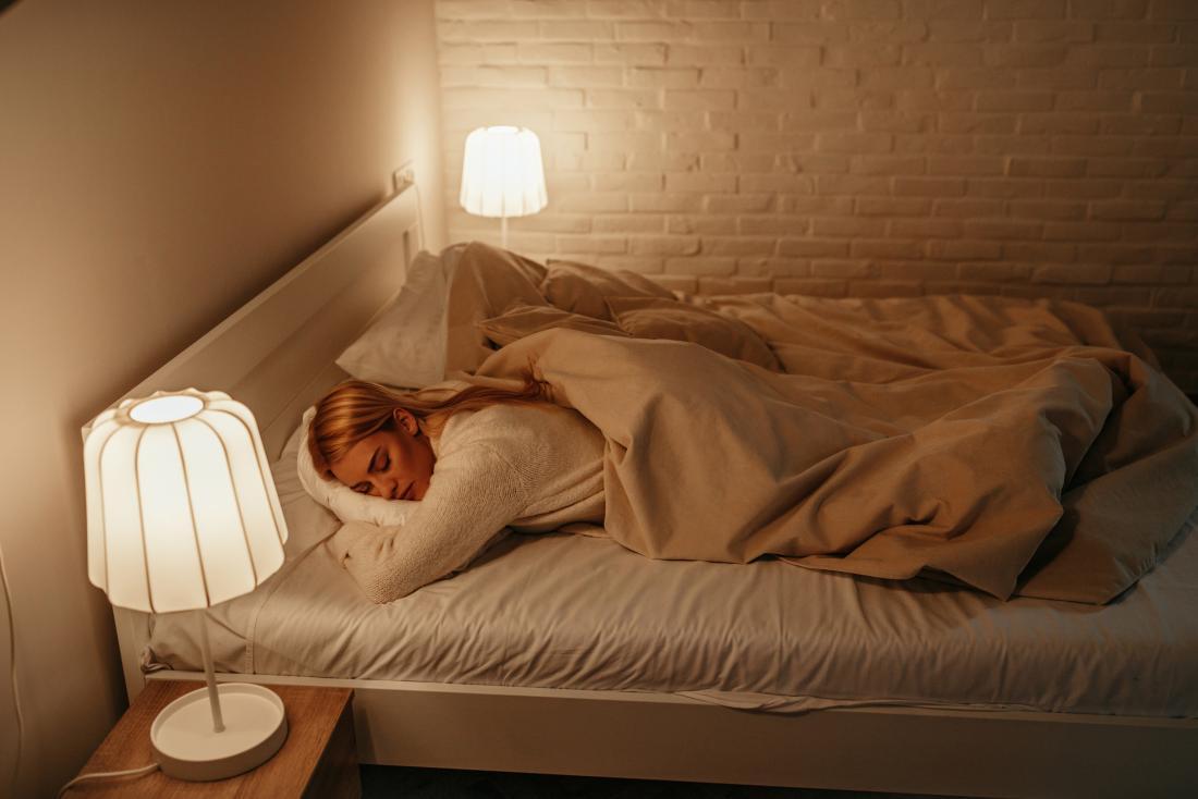 A woman sleeping with the lights on.