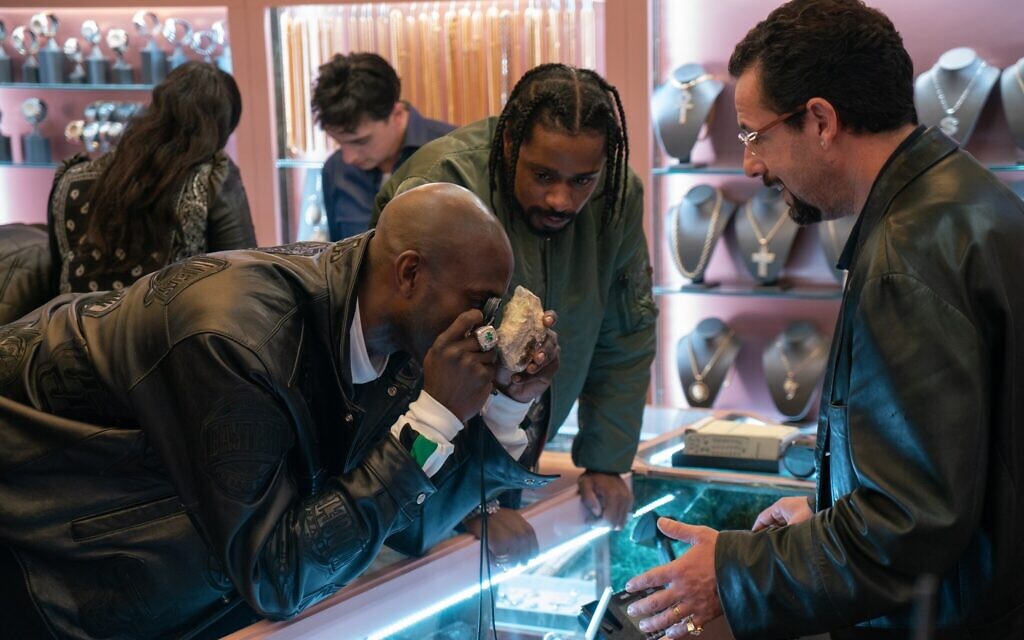Kevin Garnett closely inspects the gem while Adam Sandler looks at him.