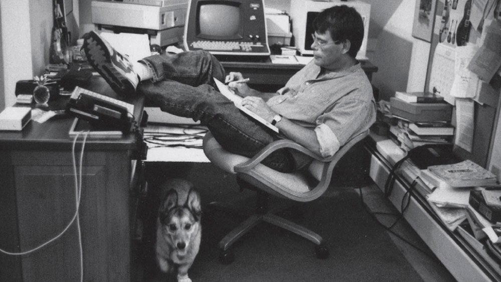 Stephen King writing from her desk, from the cover of his memoir On Writing published in 2000.