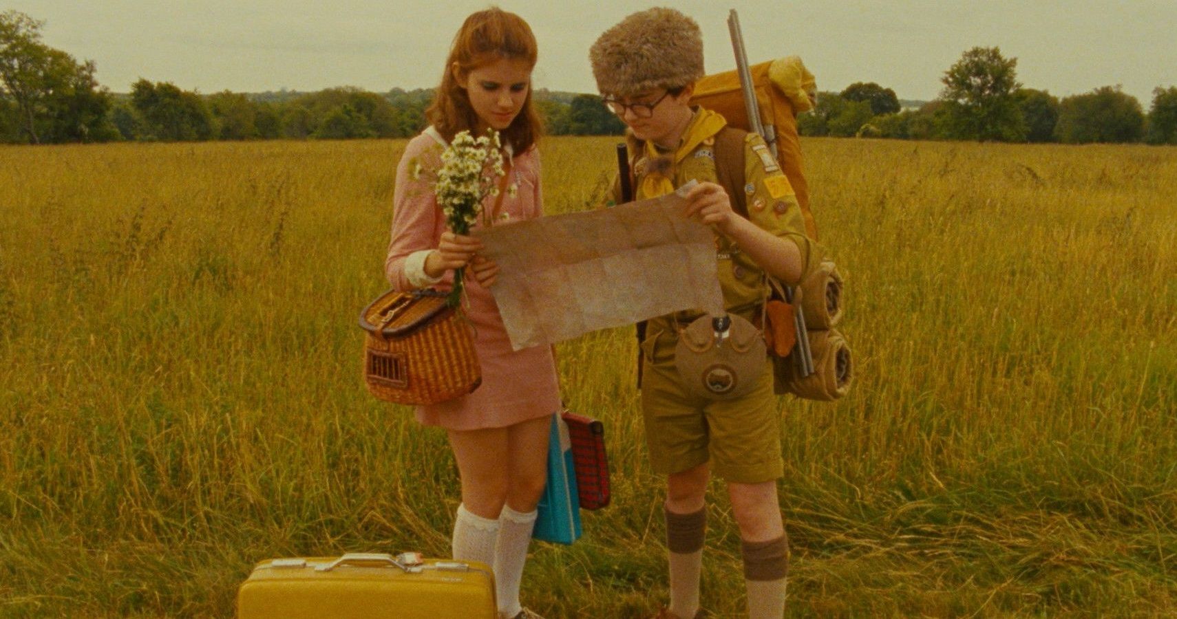 Sam Shukusky and Suzy Bishop of Wes Anderson's 2012 film Moonrise Kingdom, stand together in a field examining a map. 