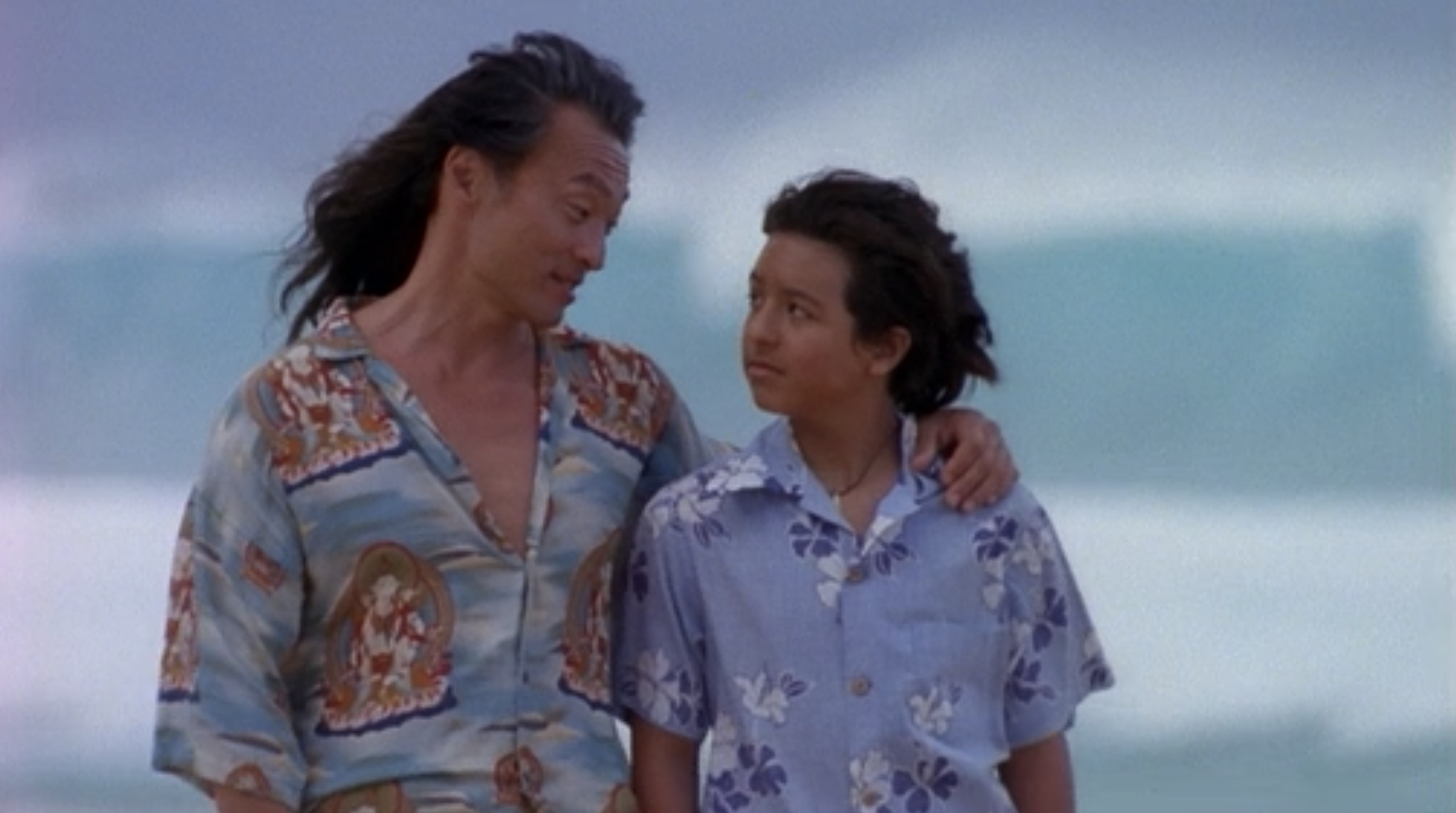 Johnny and his grandfather walk along a Hawaii beach. 