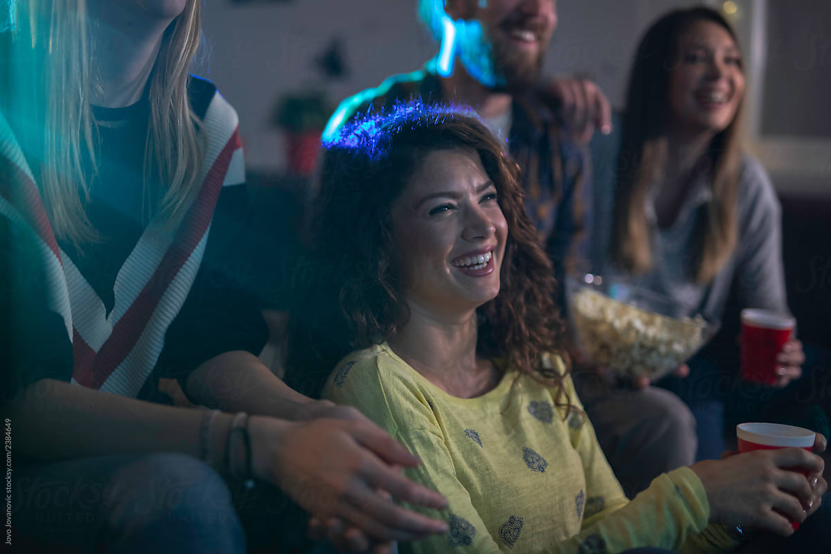 Some friends laughing while watching a movie together.