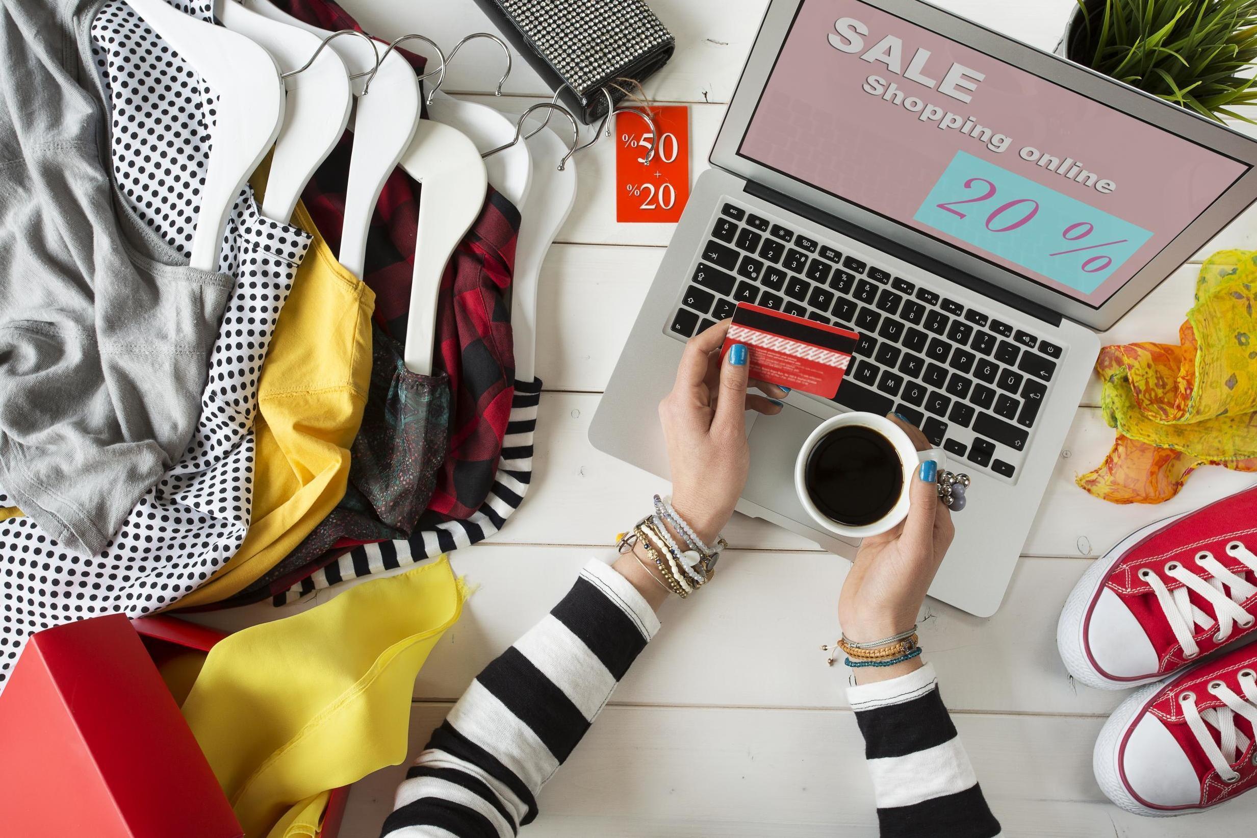 A laptop with clothing and shoes around it.