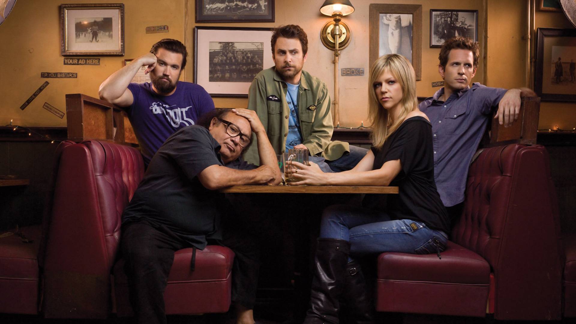 The main cast of It's Always Sunny in Philadelphia sitting in a booth at a bar.