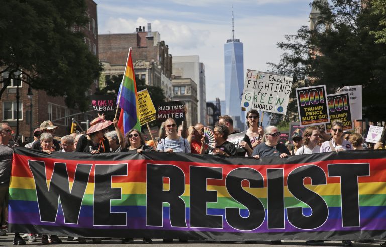 LGBTQ protestors with a banner reading "WE RESIST"