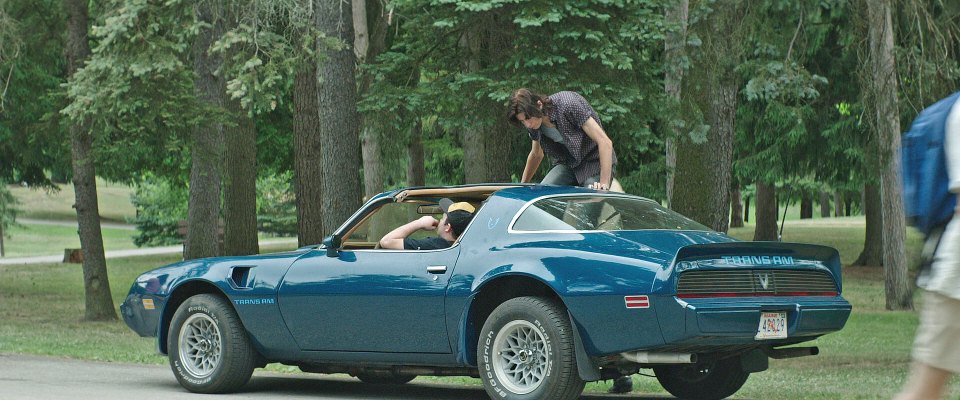 Patrick Hockstetter from the movie IT climbs out of the window of a blue car that his friend, Belch Huggins is driving.