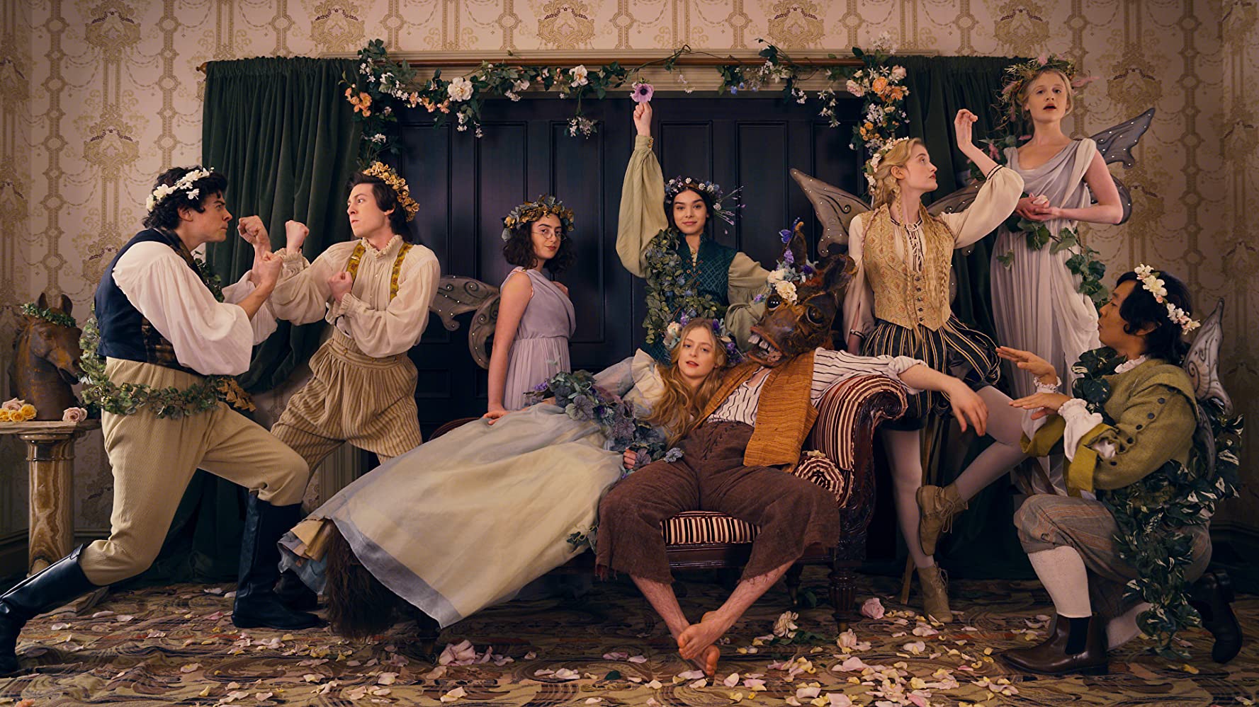 Members of the cast of Apple TV+'s show Dickinson pose around a room draped in different floral garlands.