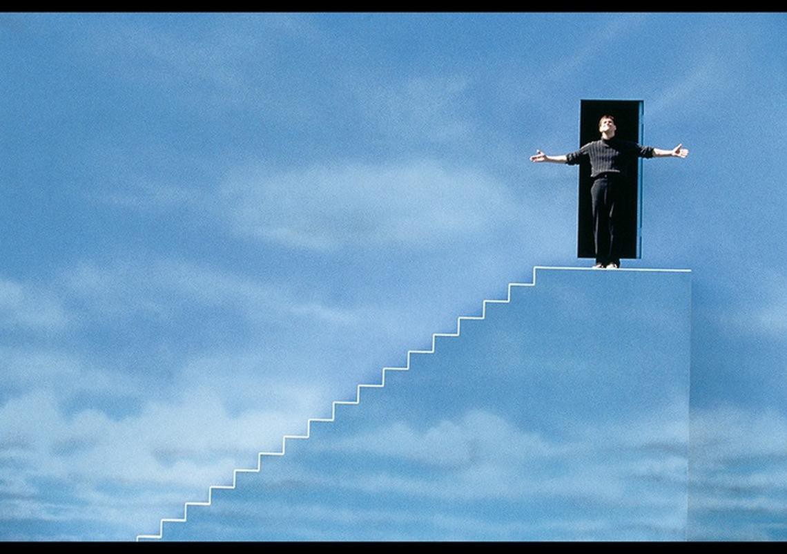 Truman stands on stairs in front of wall that was meant to seem like the distant sky. 