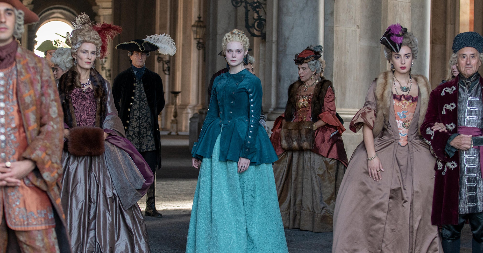 Elle Fanning as Catherine the Great stands alone amongst other members of Peter the Third's court.