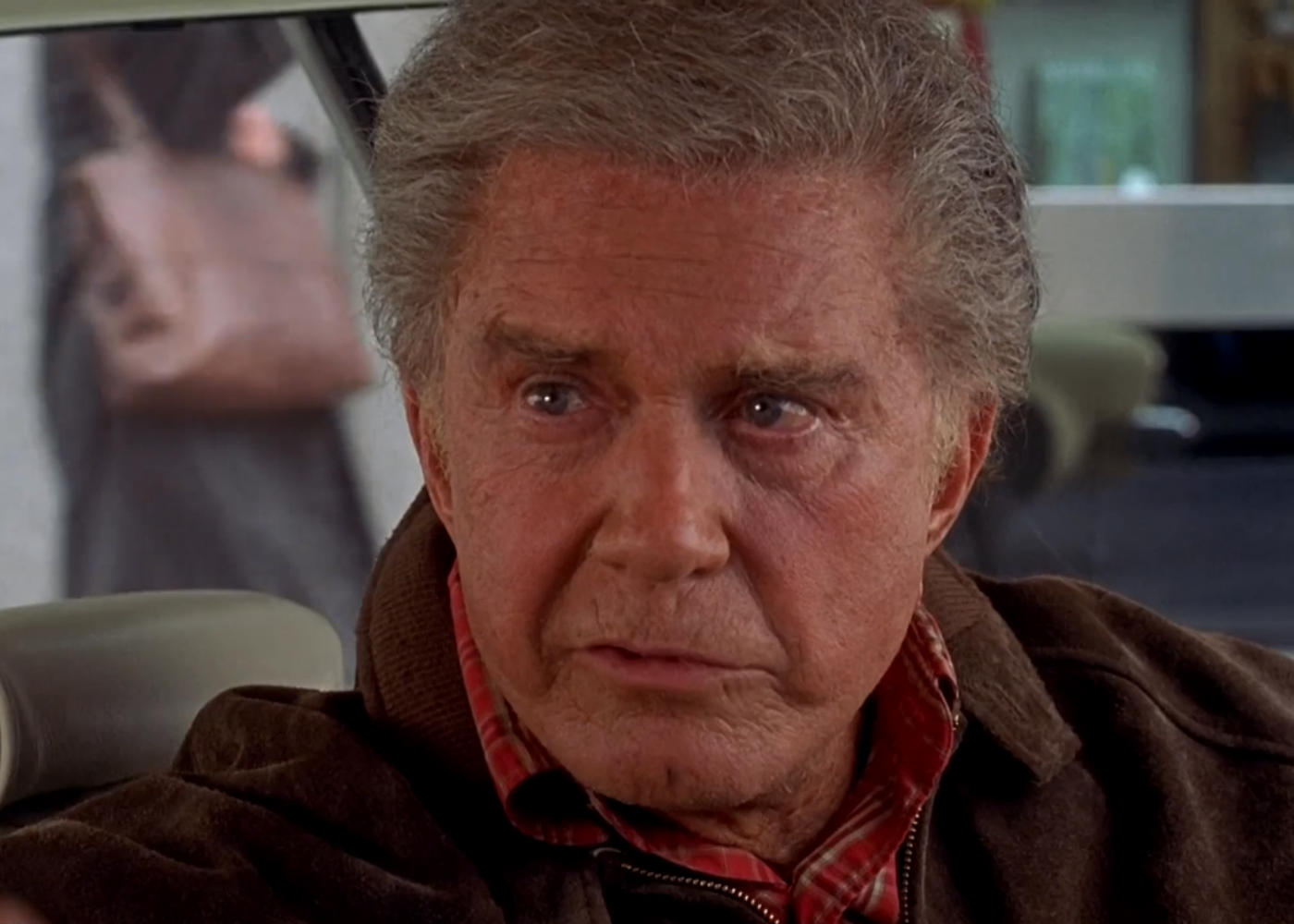 Uncle Ben sits in a car, serious.