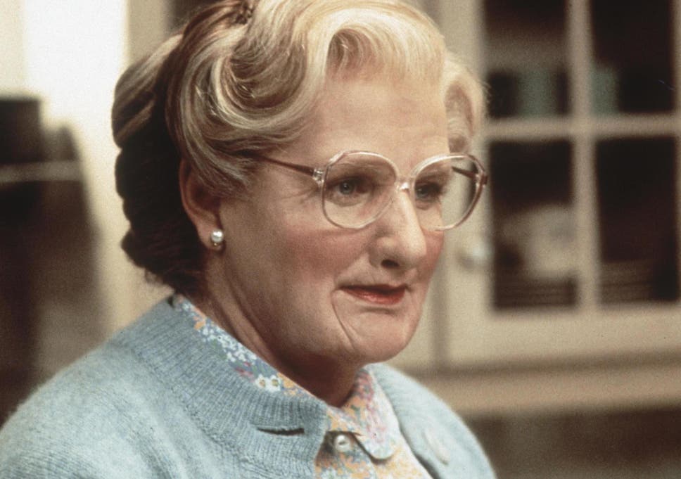 Robin Williams from the stop-and-go comedy Mrs Doubtfire dressed as an old woman with makeup, earrings, and a blue sweater. 