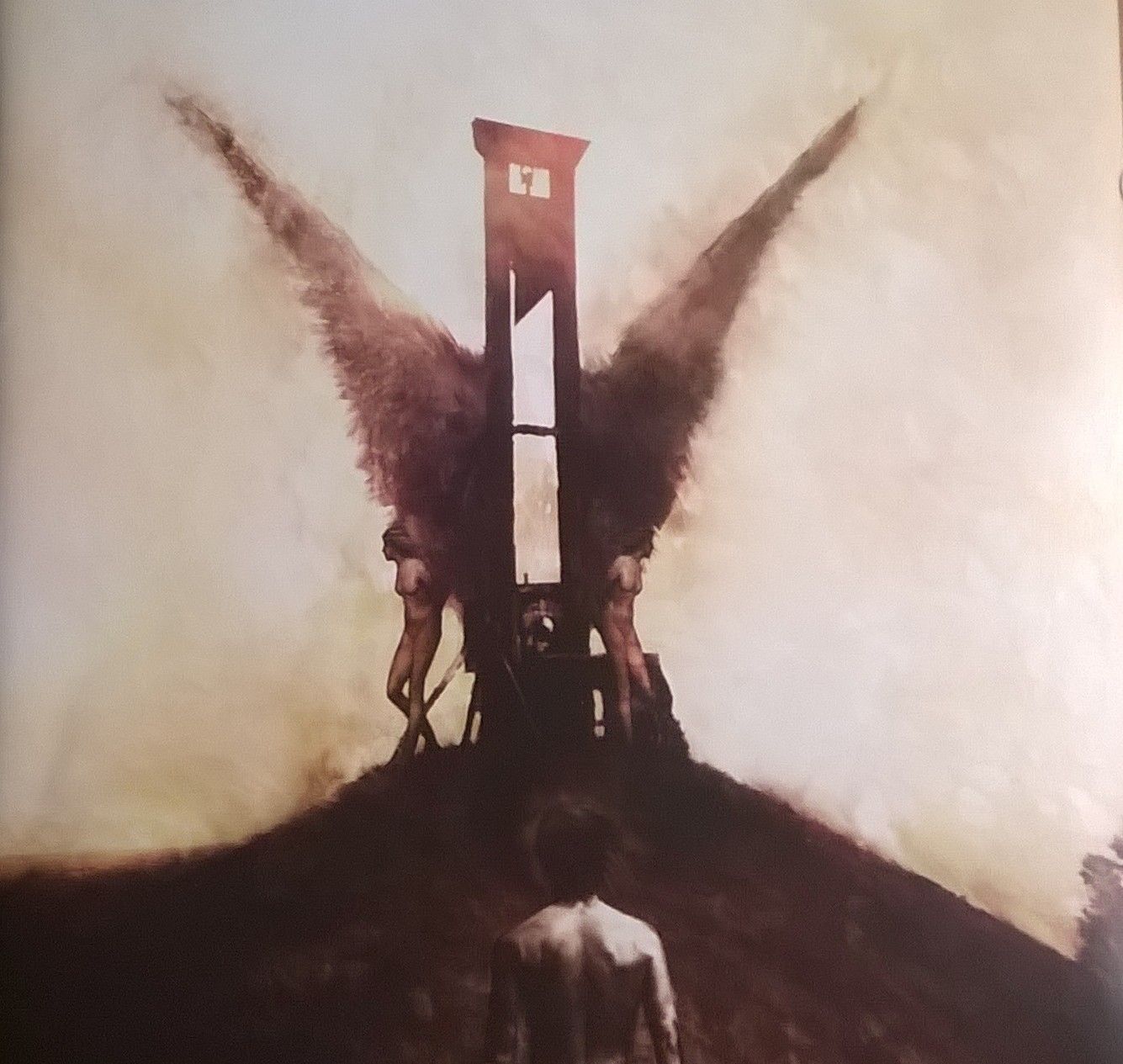 The Writer stands, facing a guillotine that has women with wings leaning against either side of it. The artwork of the Coheed and Cambria album is hazy as if it's a hallucination.