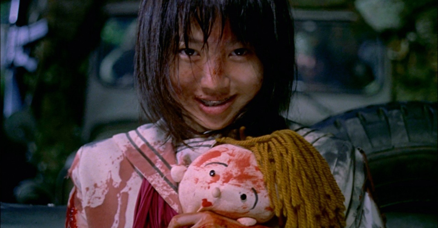 A young girl, smiling and bloody after being the winning contestant in Battle Royale.