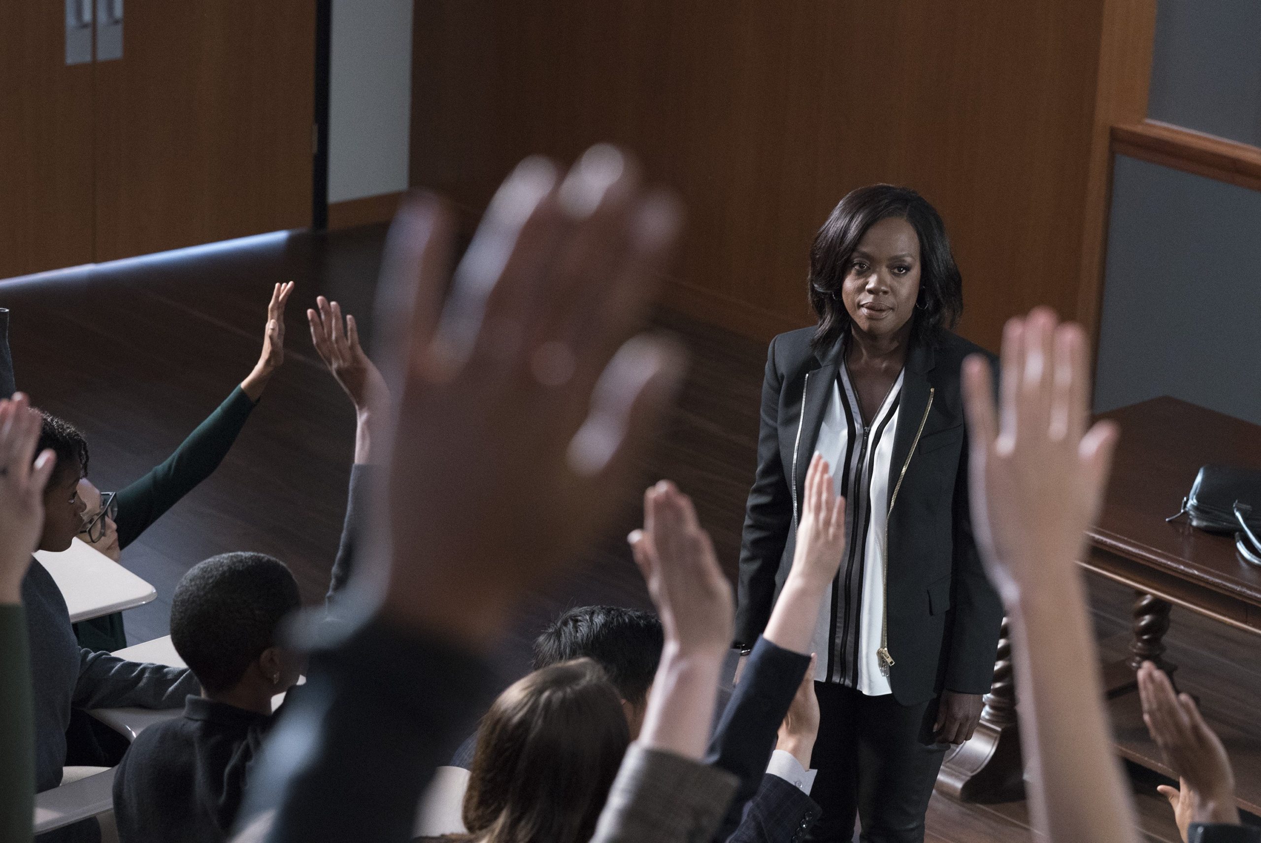 Annalise speaking during a lecture with the student's hands raised.