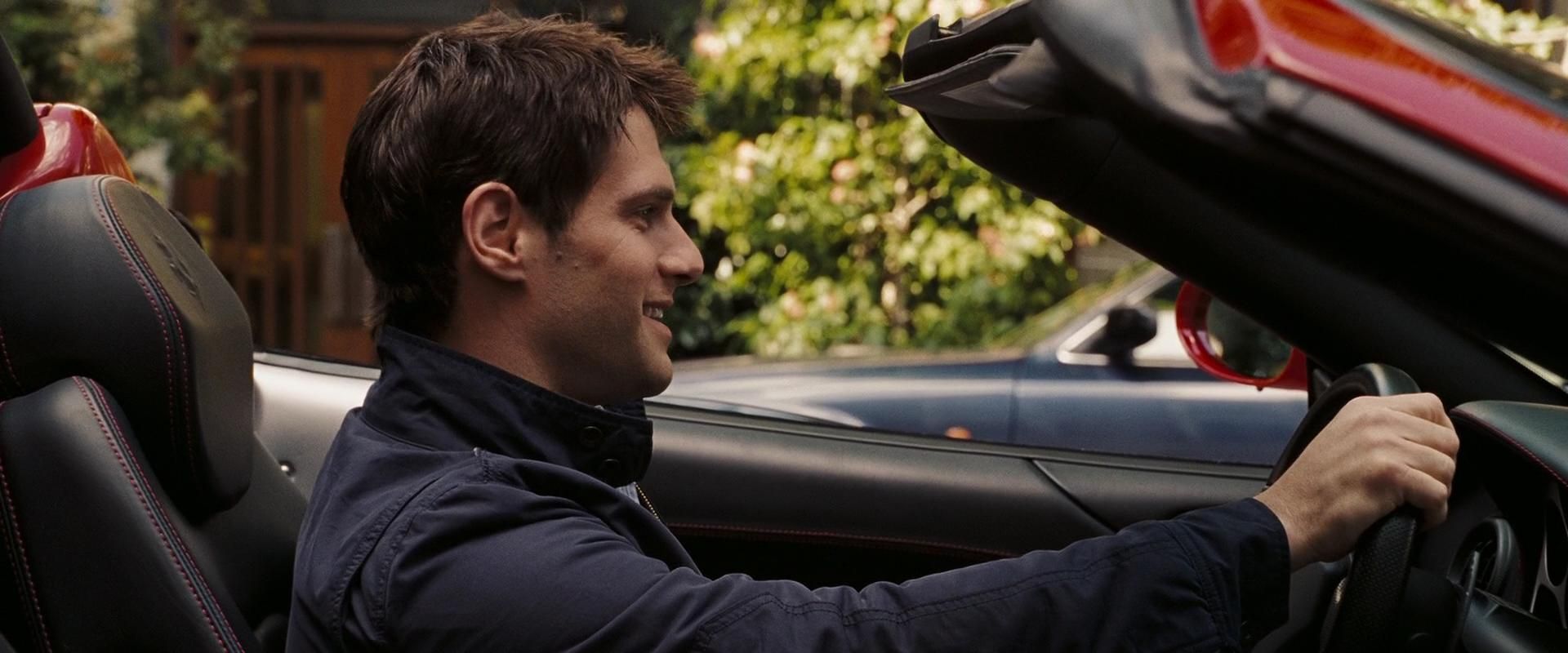 Riley Poole sits in the driver's seat of a very expensive convertible. 