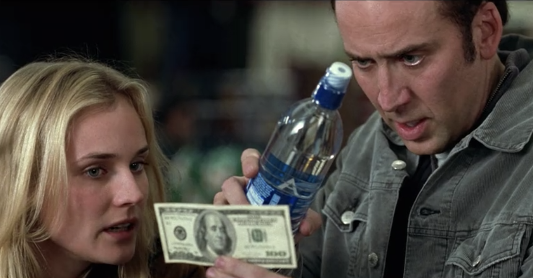 Ben Gates sends his intense and frightening stare through a water bottle and onto a hundred dollar bill below. Dr. Abigail Chase looks on.