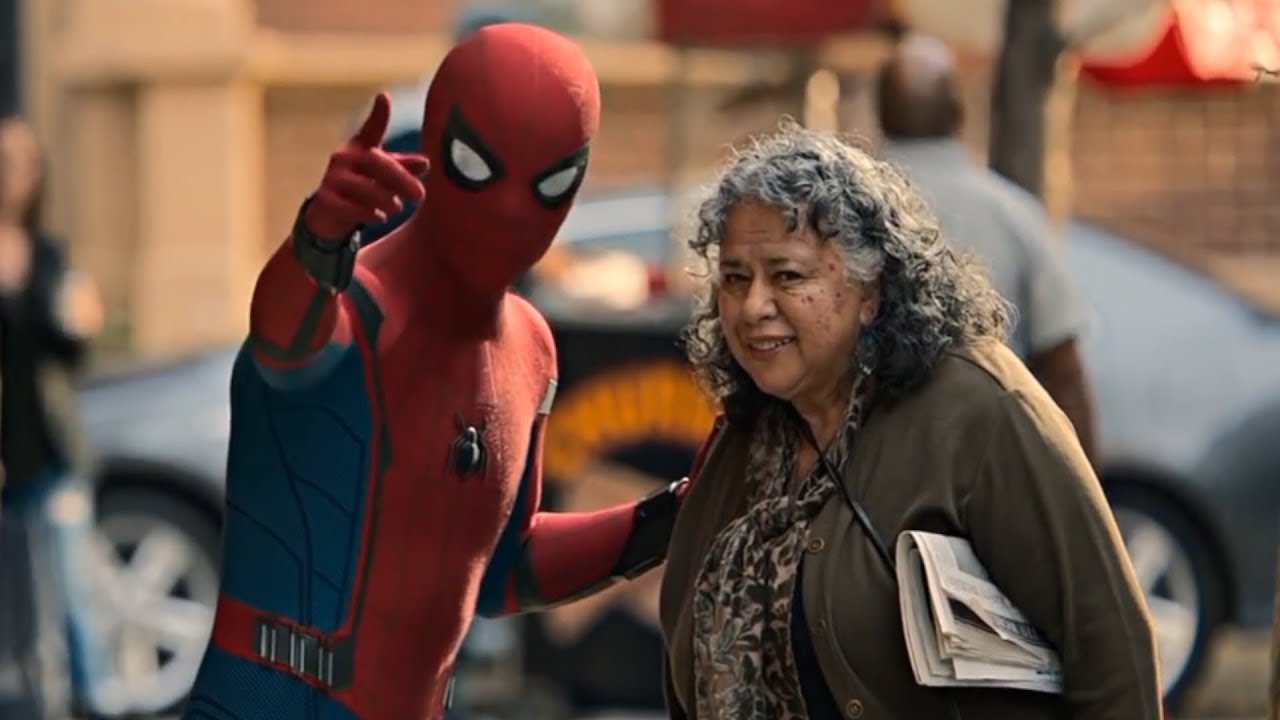 Spider-Man points forward, giving an older woman directions.