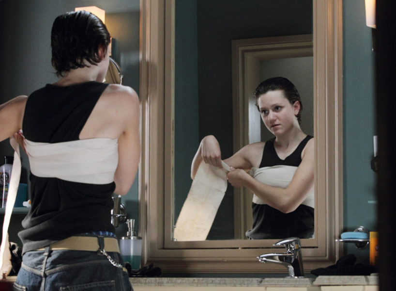 Adam Torres, Degrassi's female to male transgender characters bandages his chest in his bathroom.