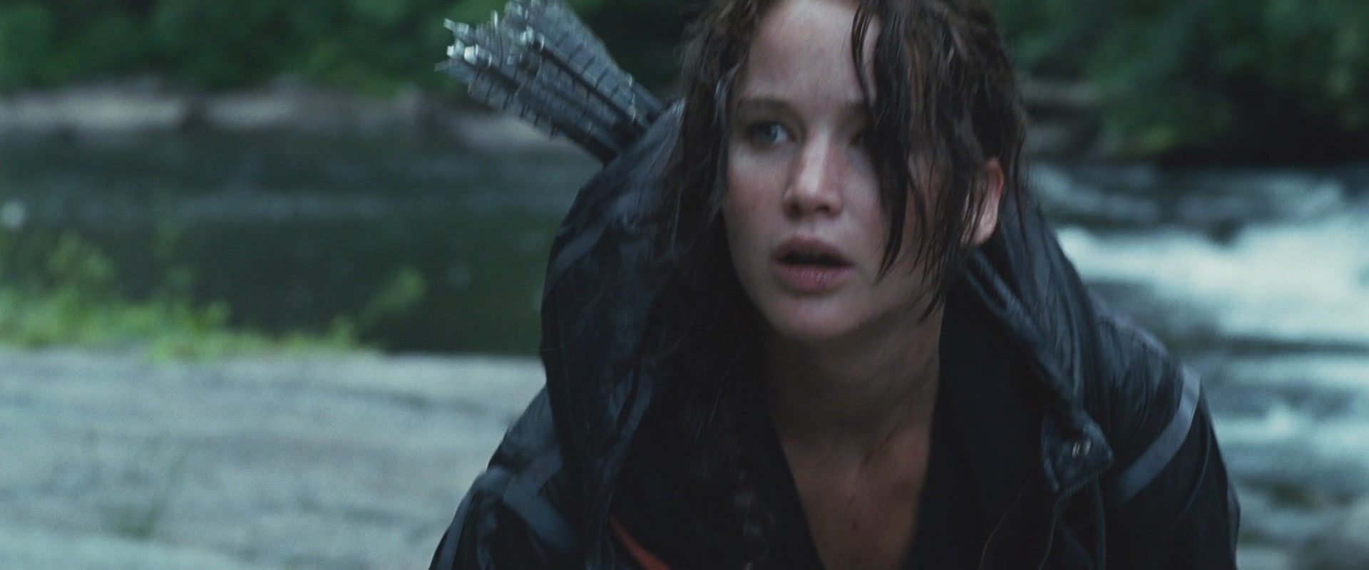 Katniss kneels near a stream during The Hunger Games.