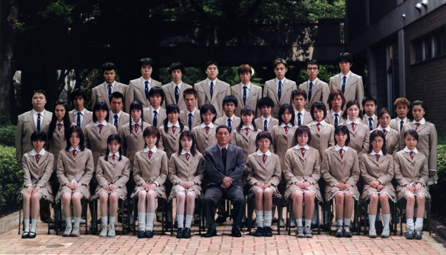 A school portrait of the Battle Royale teens in school uniforms with their teacher.