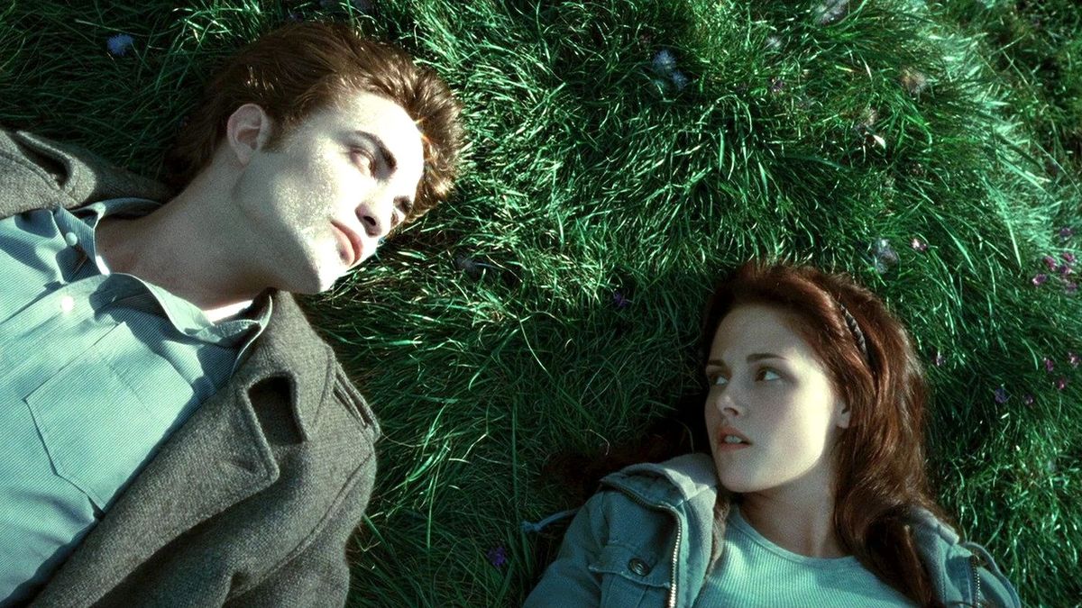 A scene from the first Twilight film where Bella is sitting on the grass with Edward as his skin sparkles in the sun.