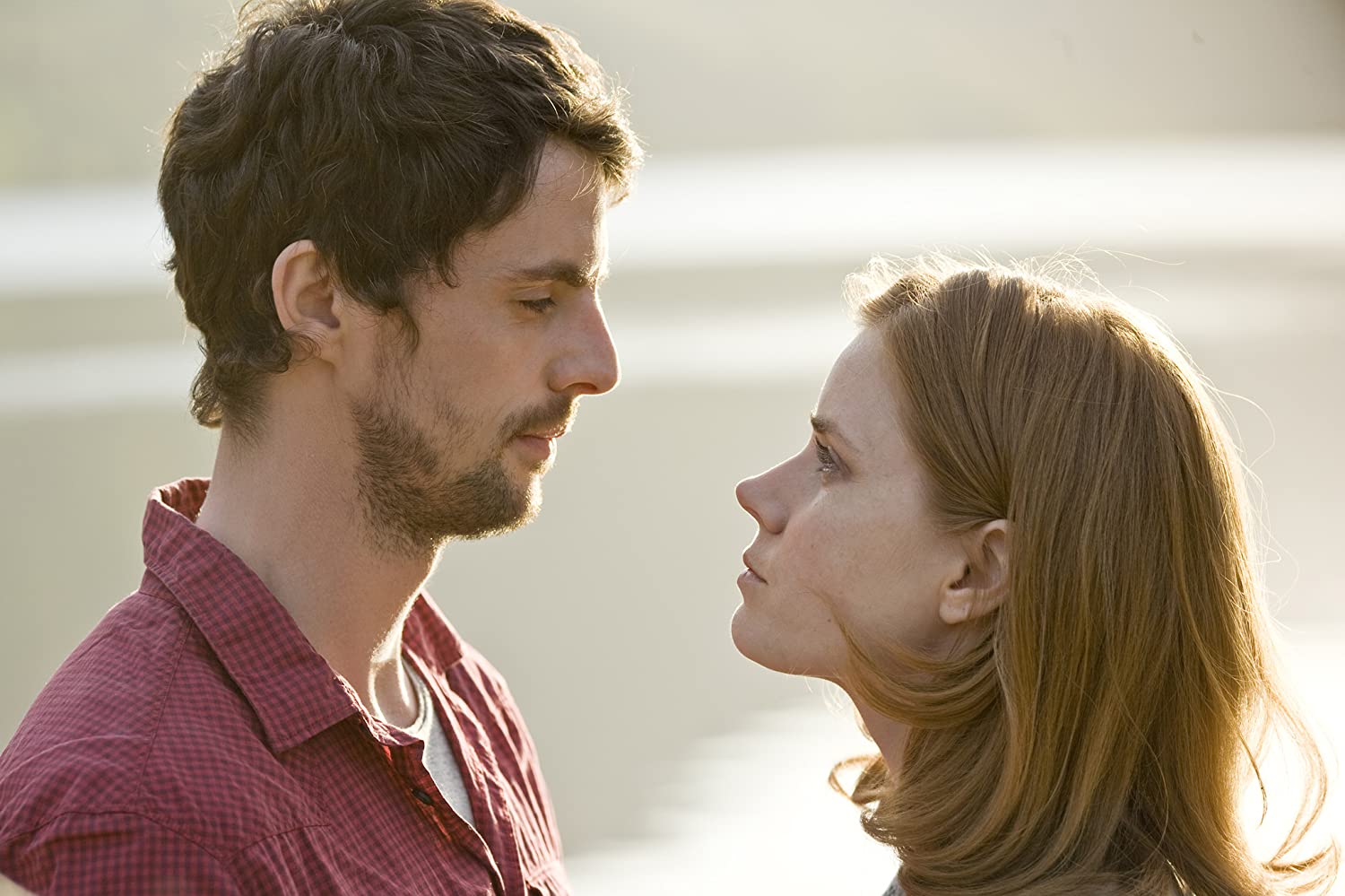 The movie's main characters stand close together looking into each others eyes.