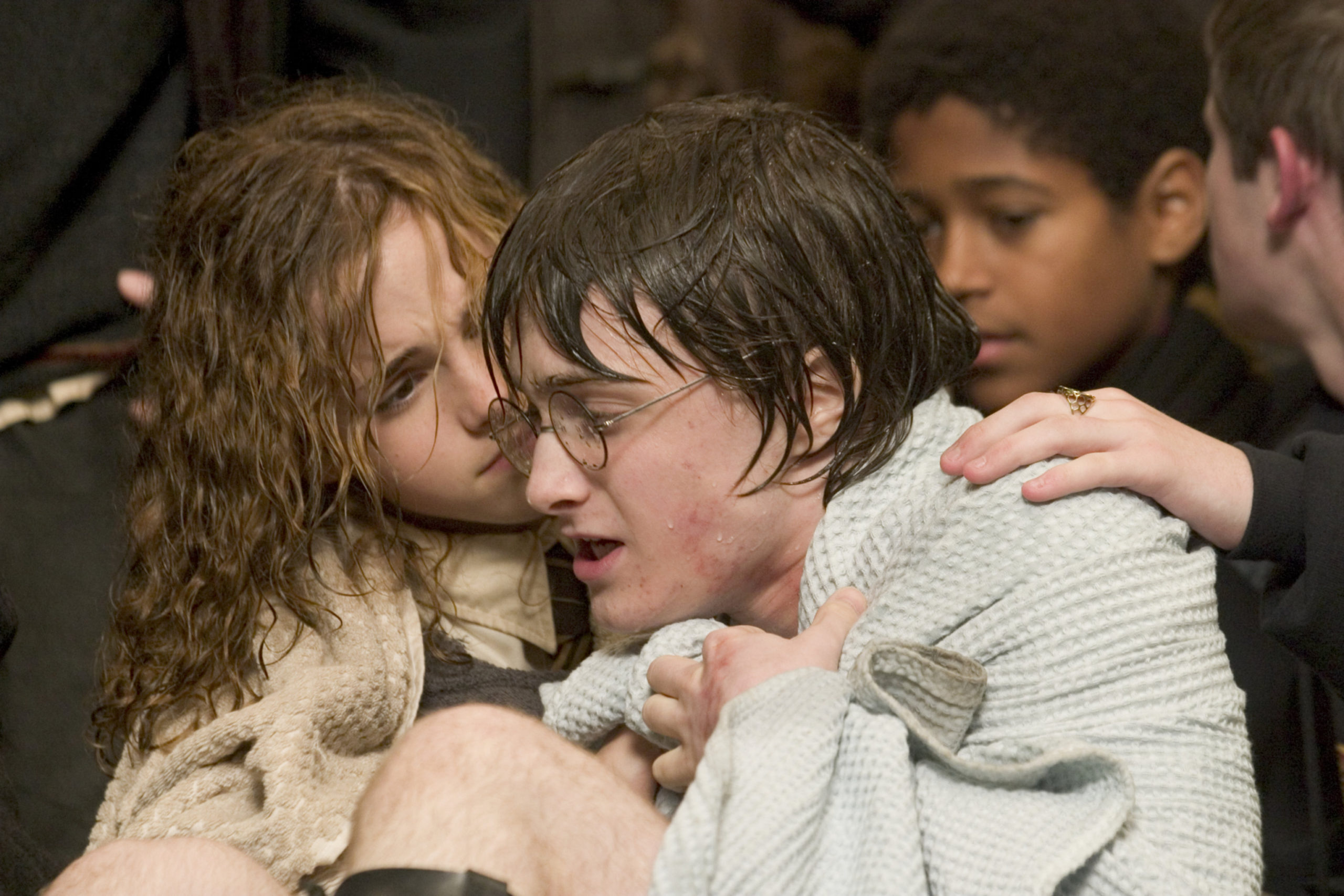 Hermione is comforting Harry, both wearing towels over them