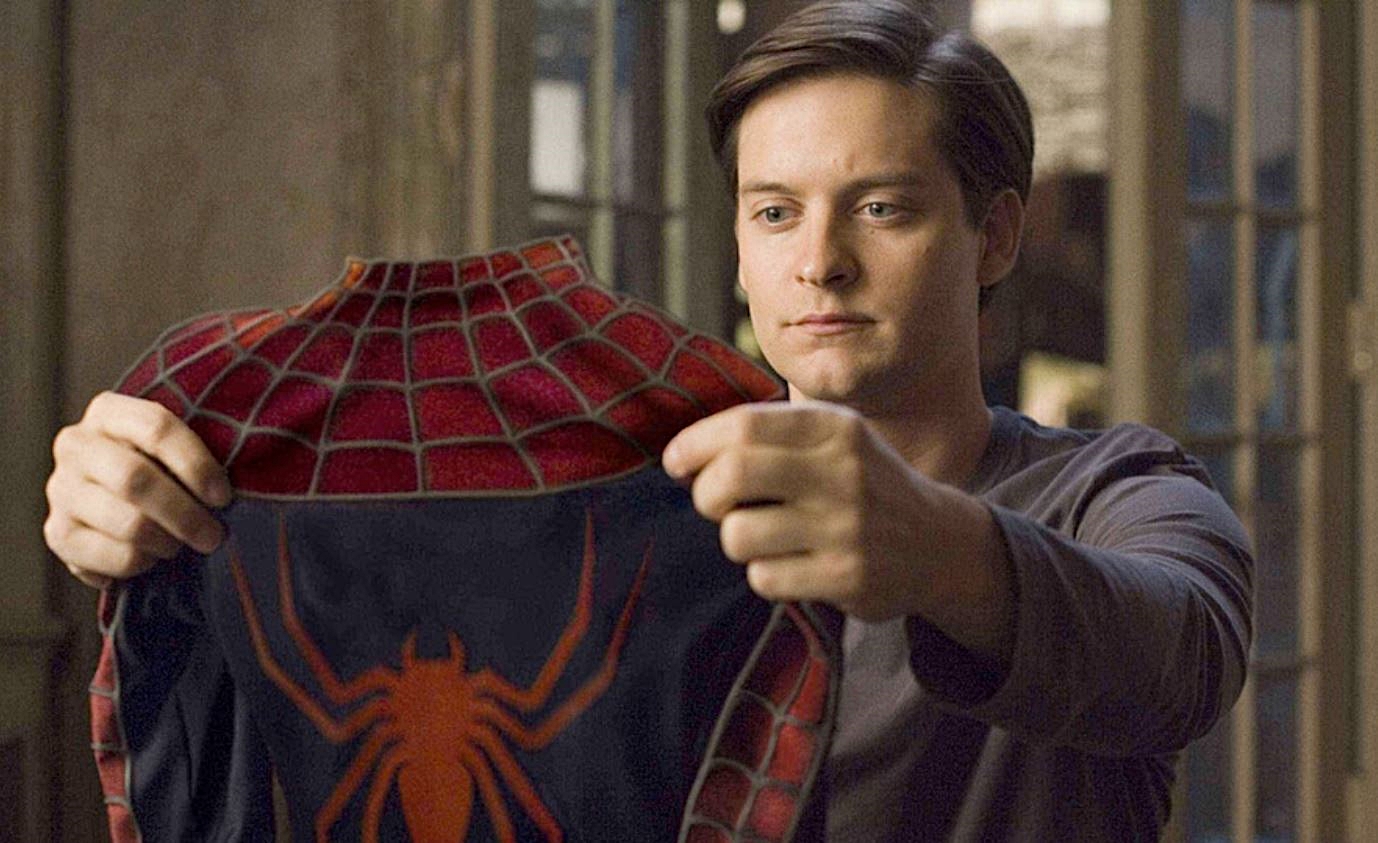 Peter Parker holds up the Spider-Man suit, examining it.