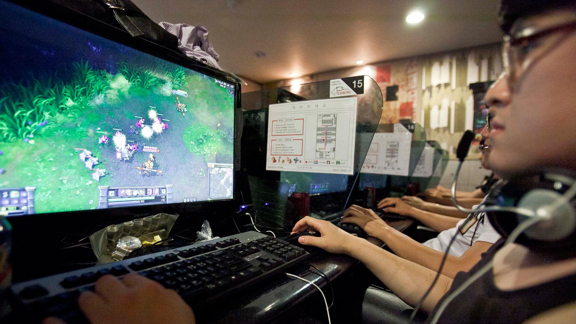 A man sits in front of a computer screen and keyboard, with gameplay on the screen.