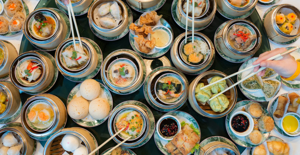 Table with multiple round dishes full of Chinese food; typical Dim Sum display.