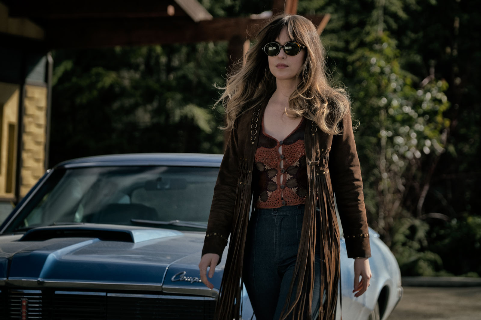 Dakota Johnson as Emily Summerspring, walks by her blue car.