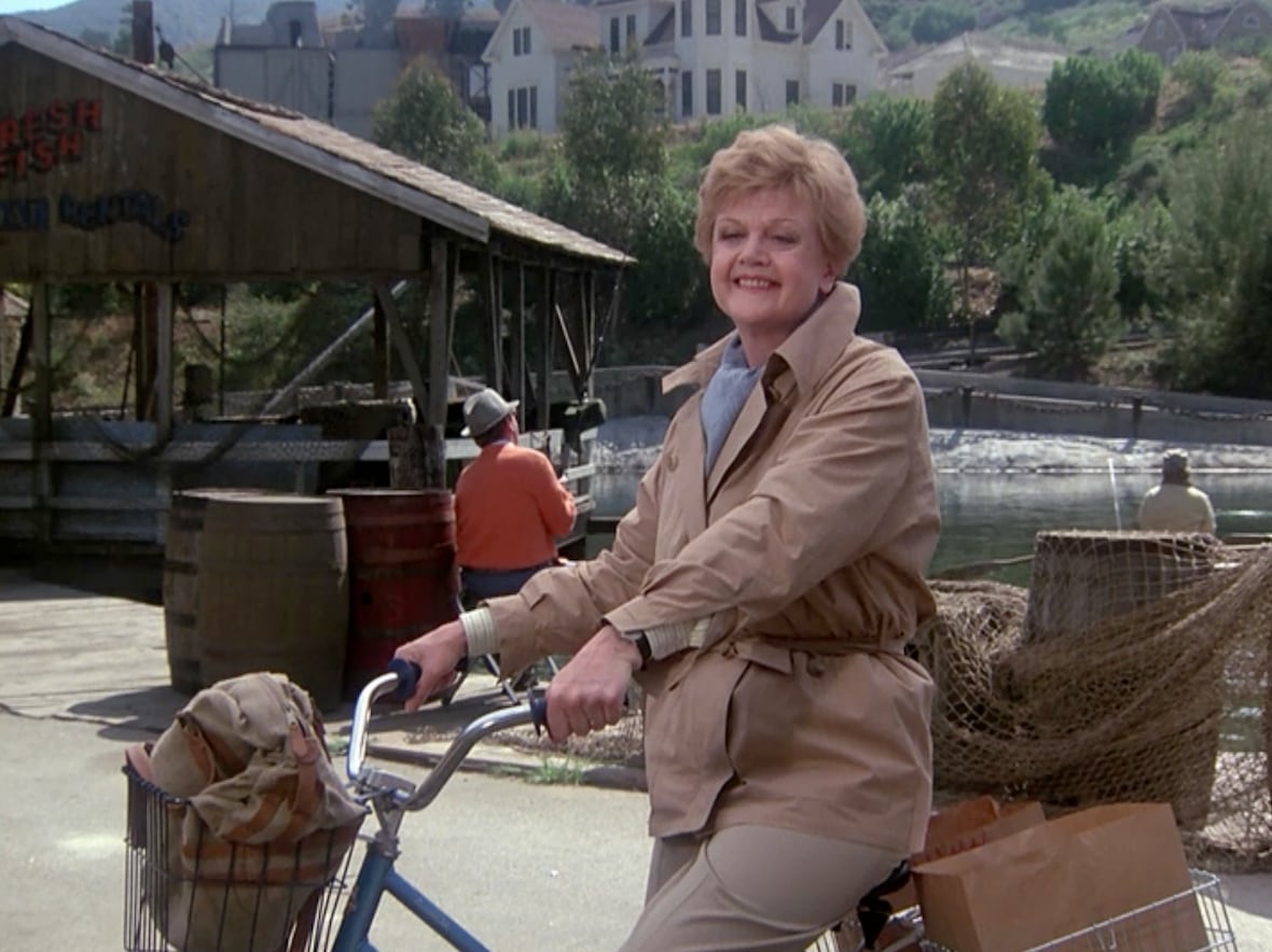 Jessica Fletcher of Murder, She Wrote, smiling and riding her bike in Cabot Cove.