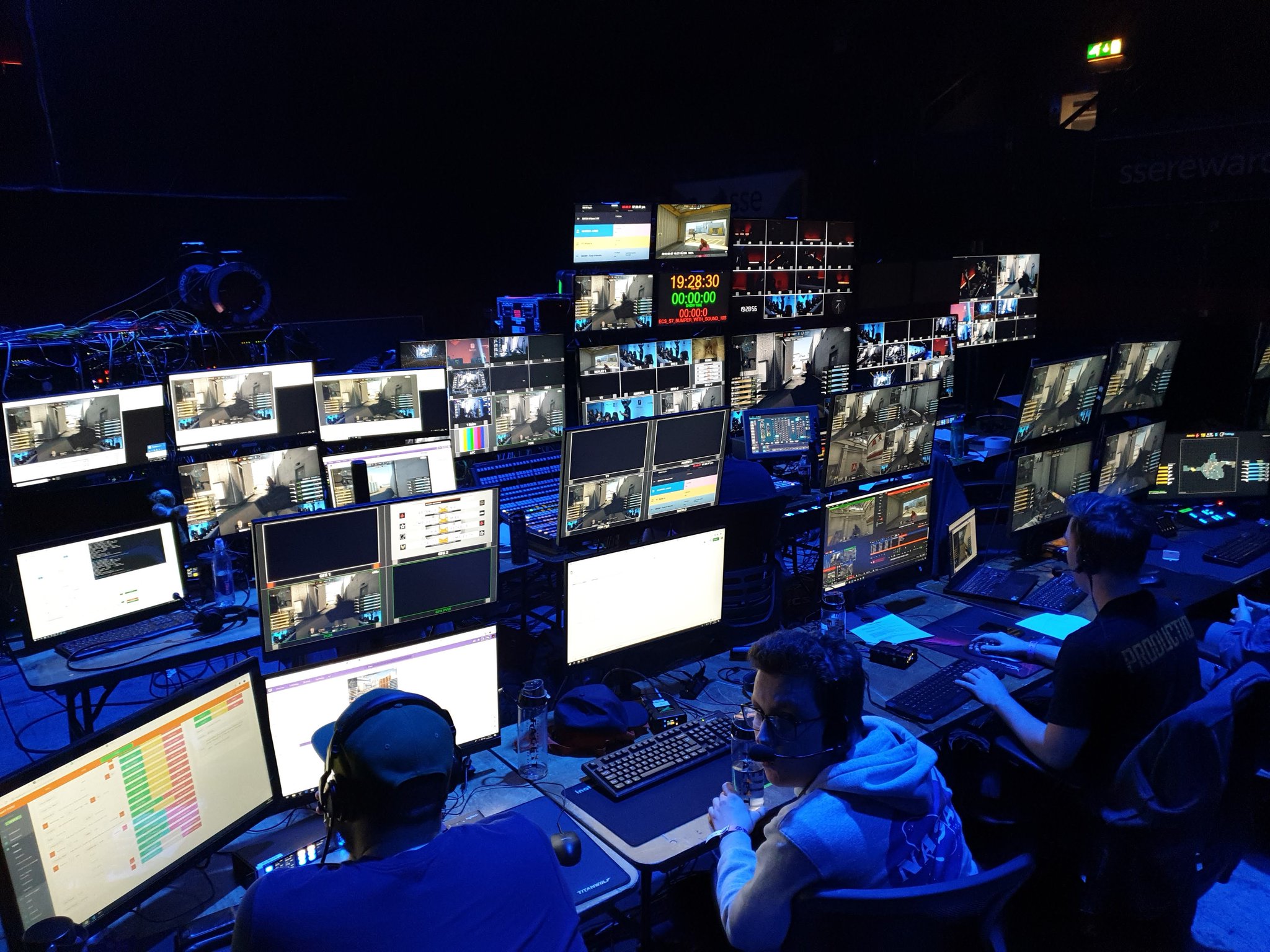 A cluster of computers and monitors backstage at a FACEIT event.