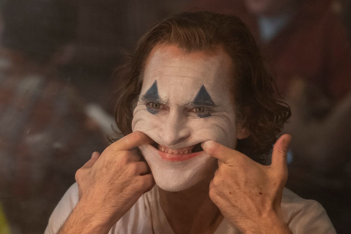 The Joker forces a smile with his fingers.