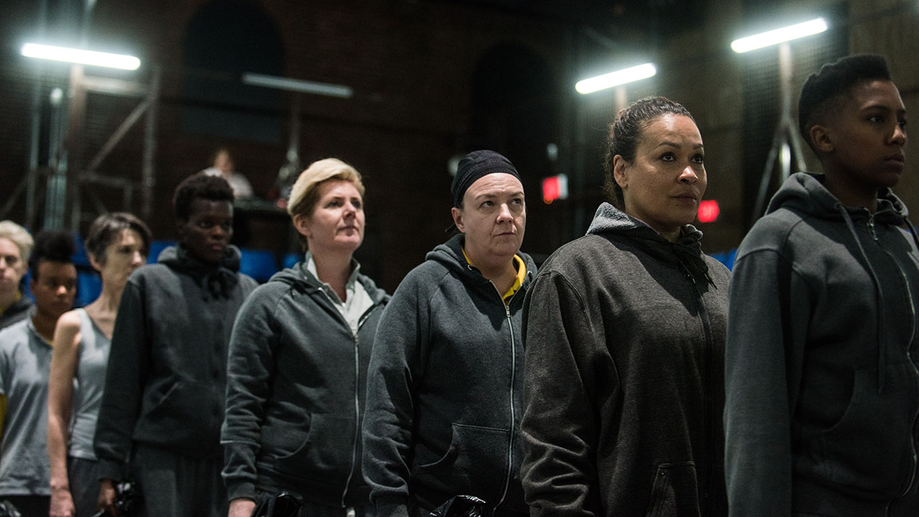 The cast of Donmar Warehouse's The Tempest stands single file in a line. 