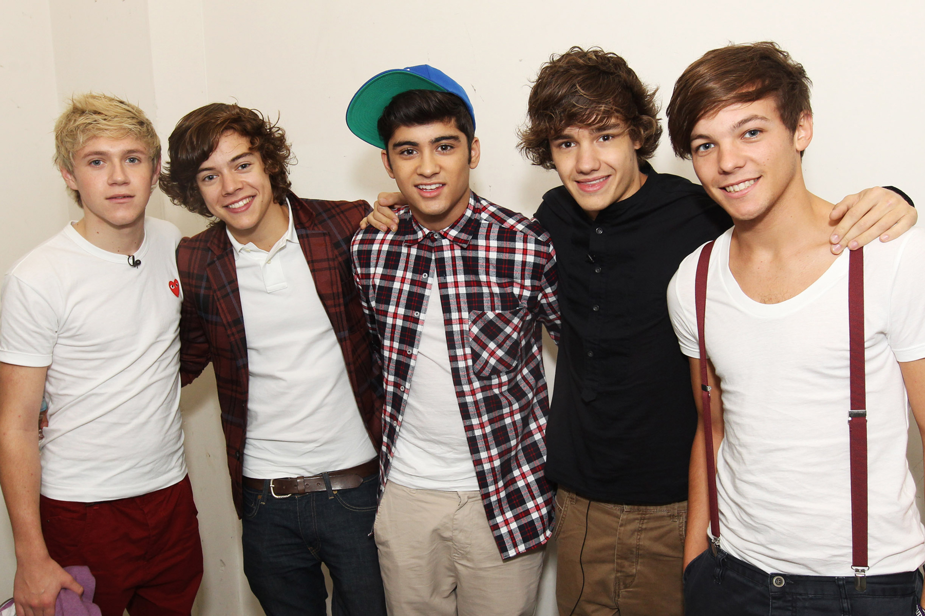 One Direction members Niall, Harry, Zayn, Liam, and Louis posing for camera.