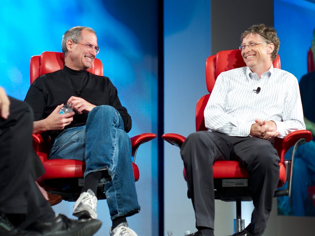 Bill Gates and Steve Jobs sit side by side in red chairs. 