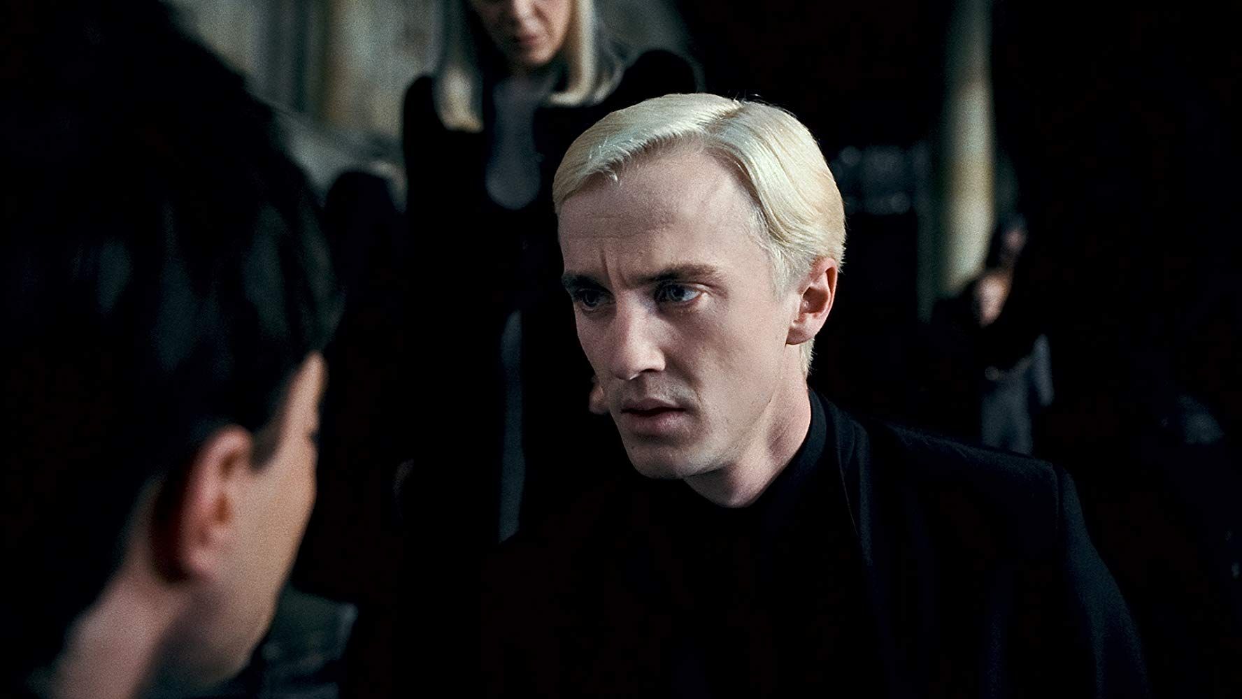 Draco Malfoy stares sadly at a boy.