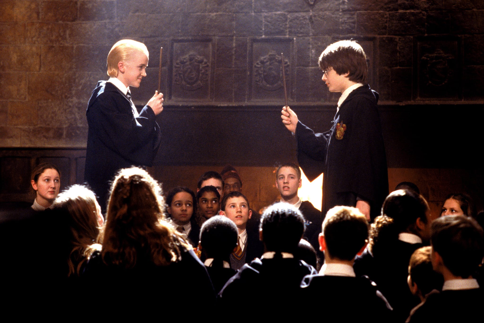 Draco Malfoy and Harry Potter stand face-to-face with their wands up as they wait to start dueling.