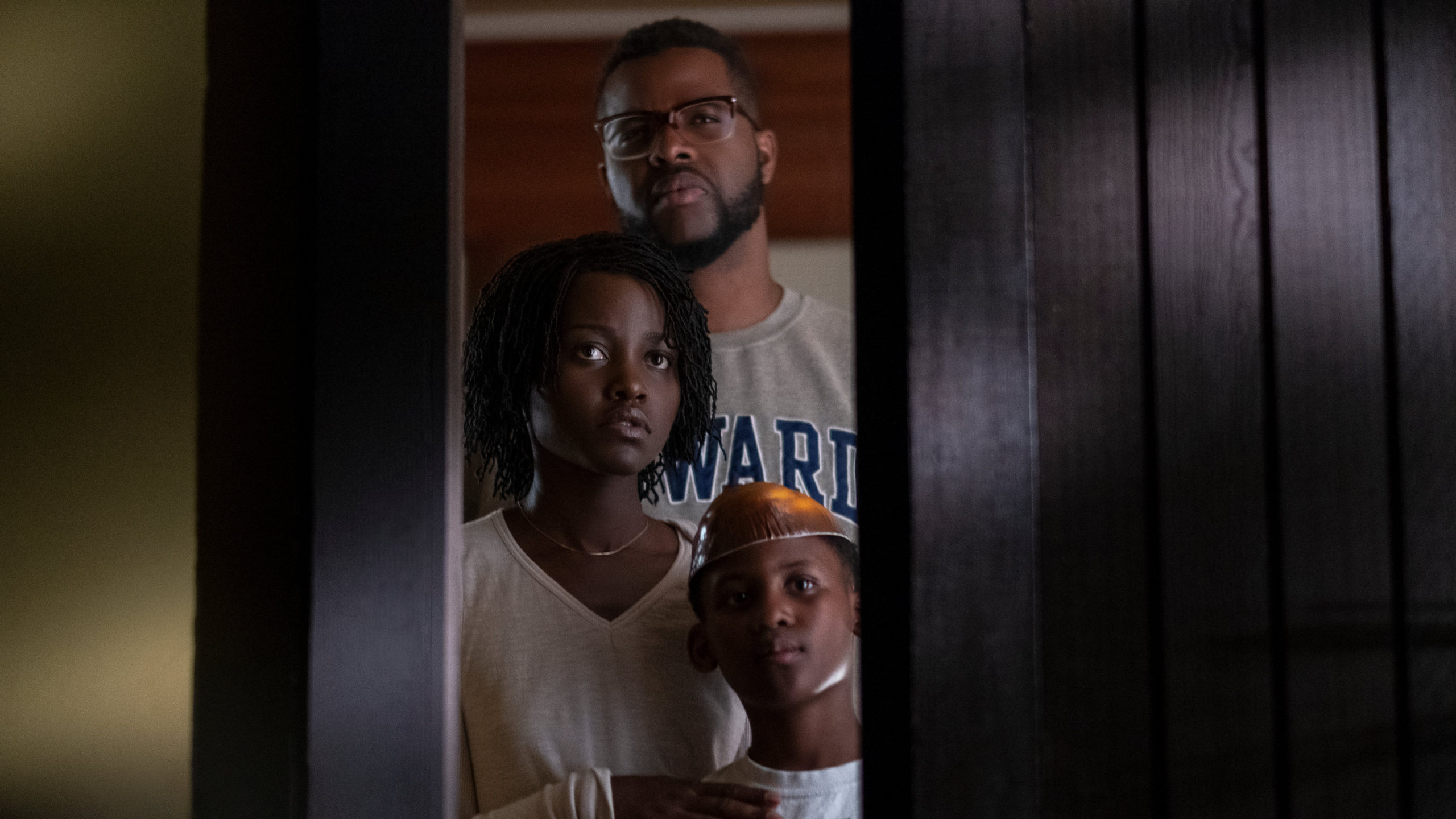 Red, her husband, and her son look through the window at their doppelgängers in the front yard.