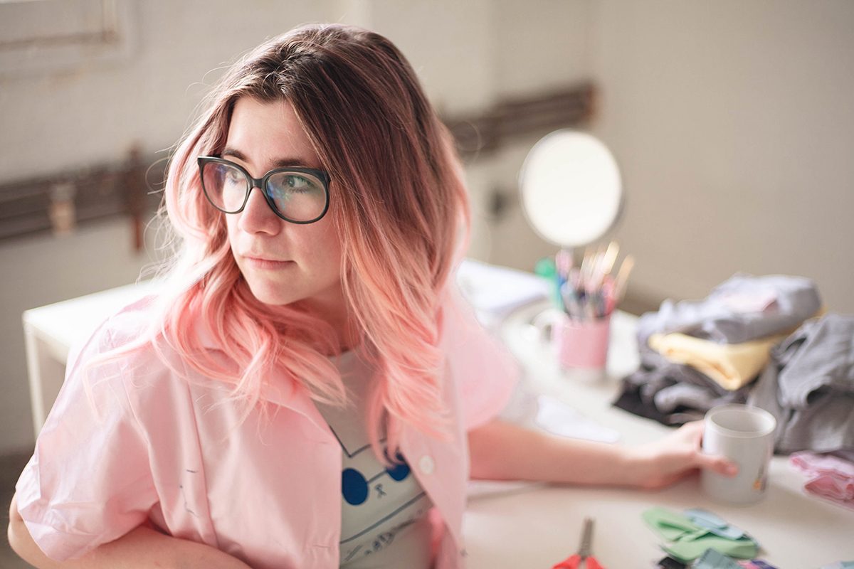 YouTube artist Fran Meneses looking over her shoulder while sitting at her studio table. 